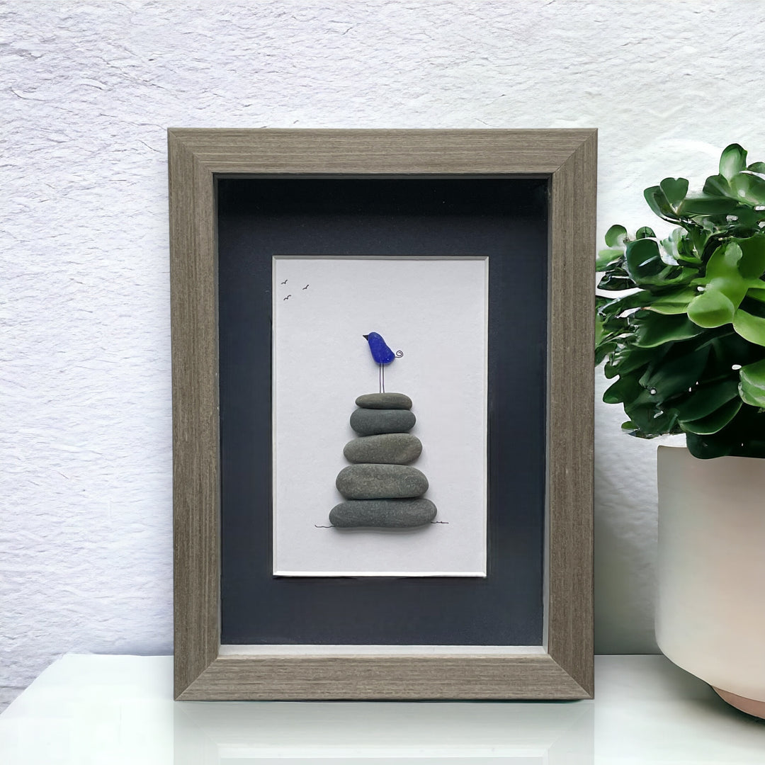 Pájaro de cristal marino azul sobre rocas de equilibrio Arte reciclado de guijarros