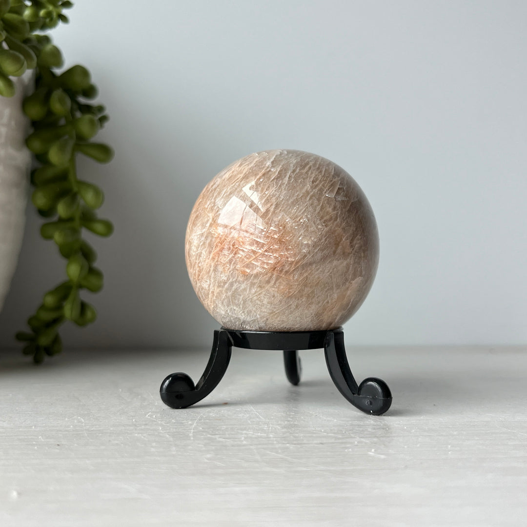 Esfera de piedra lunar de melocotón en un lindo soporte
