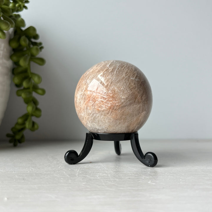 Esfera de piedra lunar de melocotón en un lindo soporte