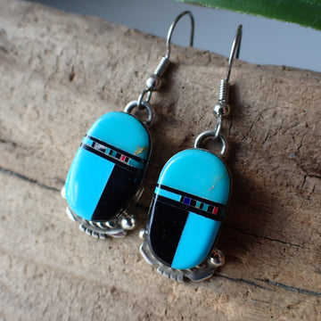 sterling silver blue and black inlaid oval earrings displayed on driftwood
