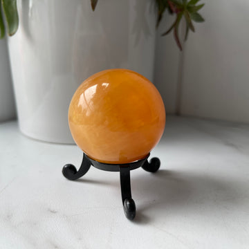 orange calcite crystal stone sphere on stand