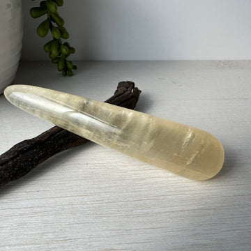 honey calcite smooth wand displayed on driftwood