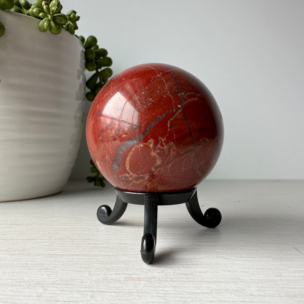 red jasper stone sphere on black stand